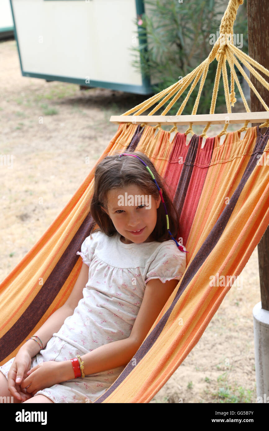 beautiful little girl with long brown hair resting on a hammock in the summer Stock Photo