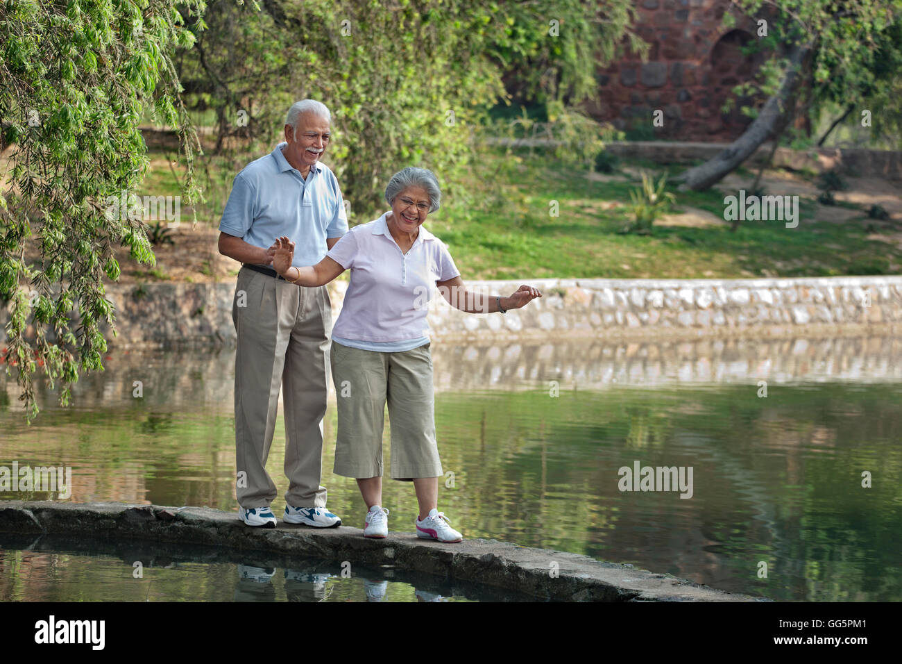 Careful mature woman balancing while walking with man in park Stock Photo