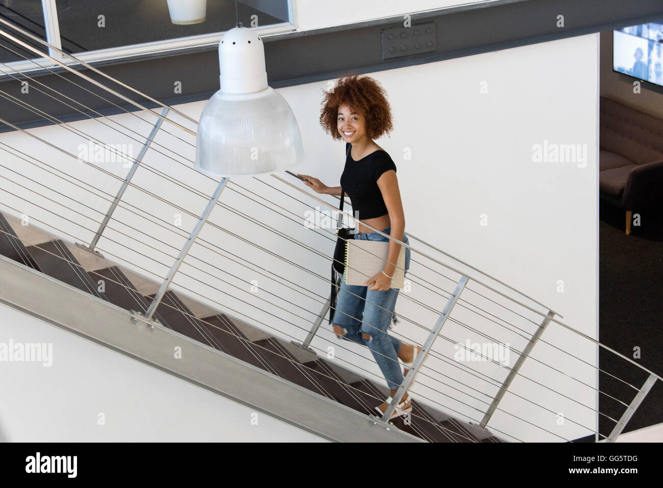 Portrait of a young woman moving up staircase Stock Photo