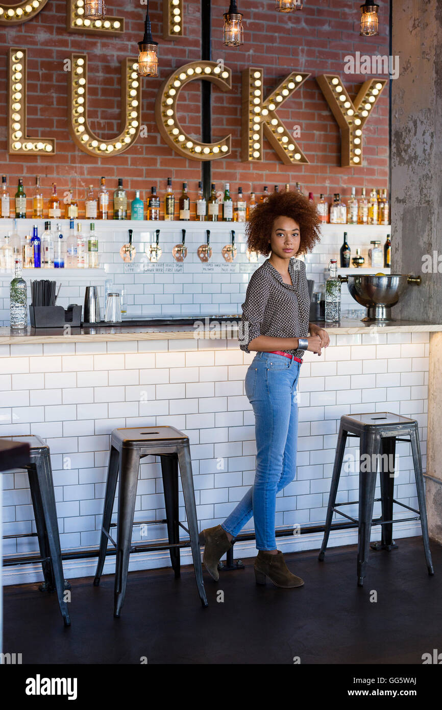 Portrait of a young woman standing at bar counter Stock Photo