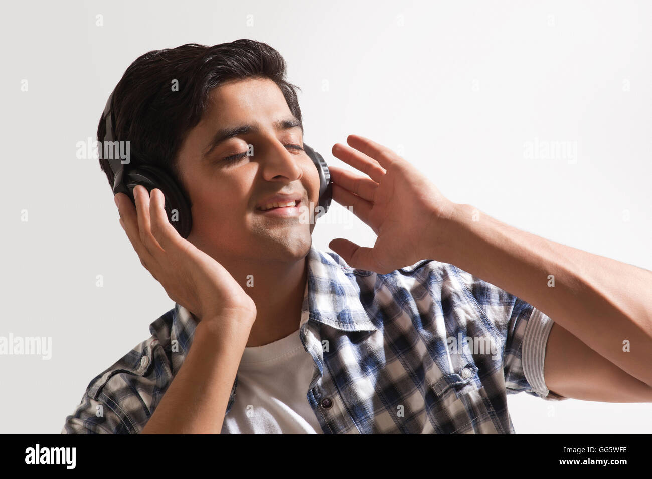Relaxed young guy listening music over colored background Stock Photo