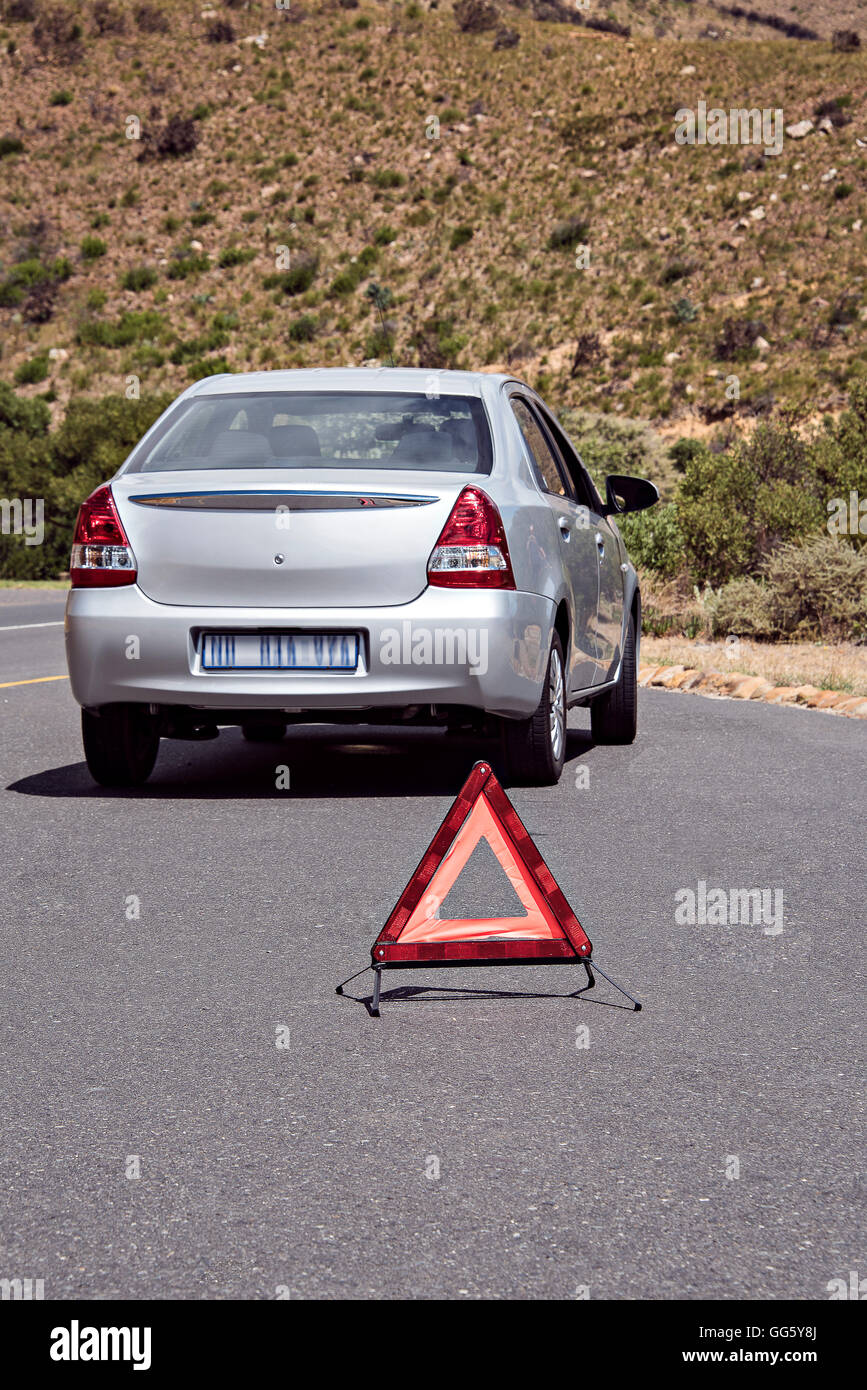 Warning triangle sign near breakdown car on road Stock Photo