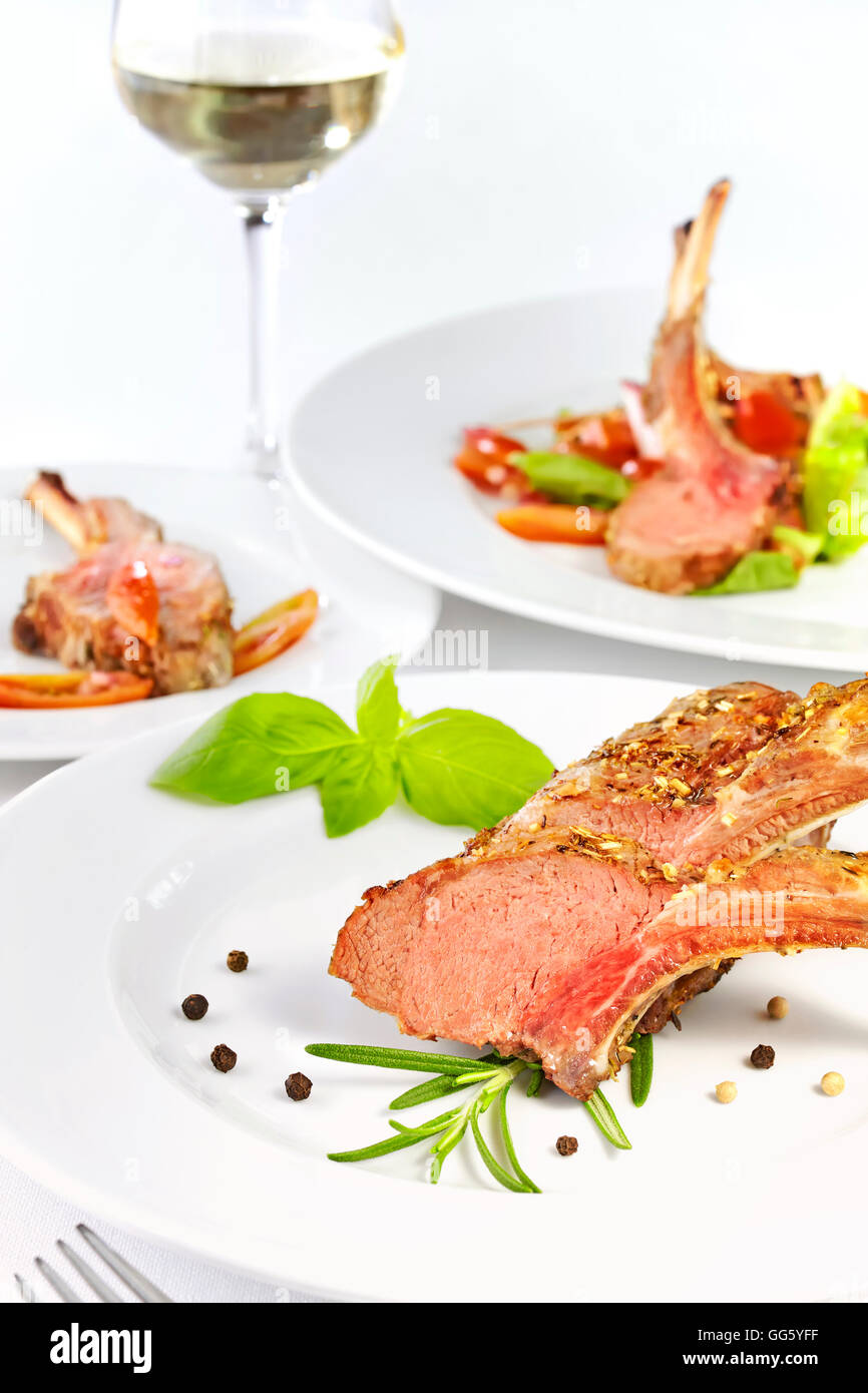 Roasted lamb rib chops, dinner setting with white vine. Stock Photo