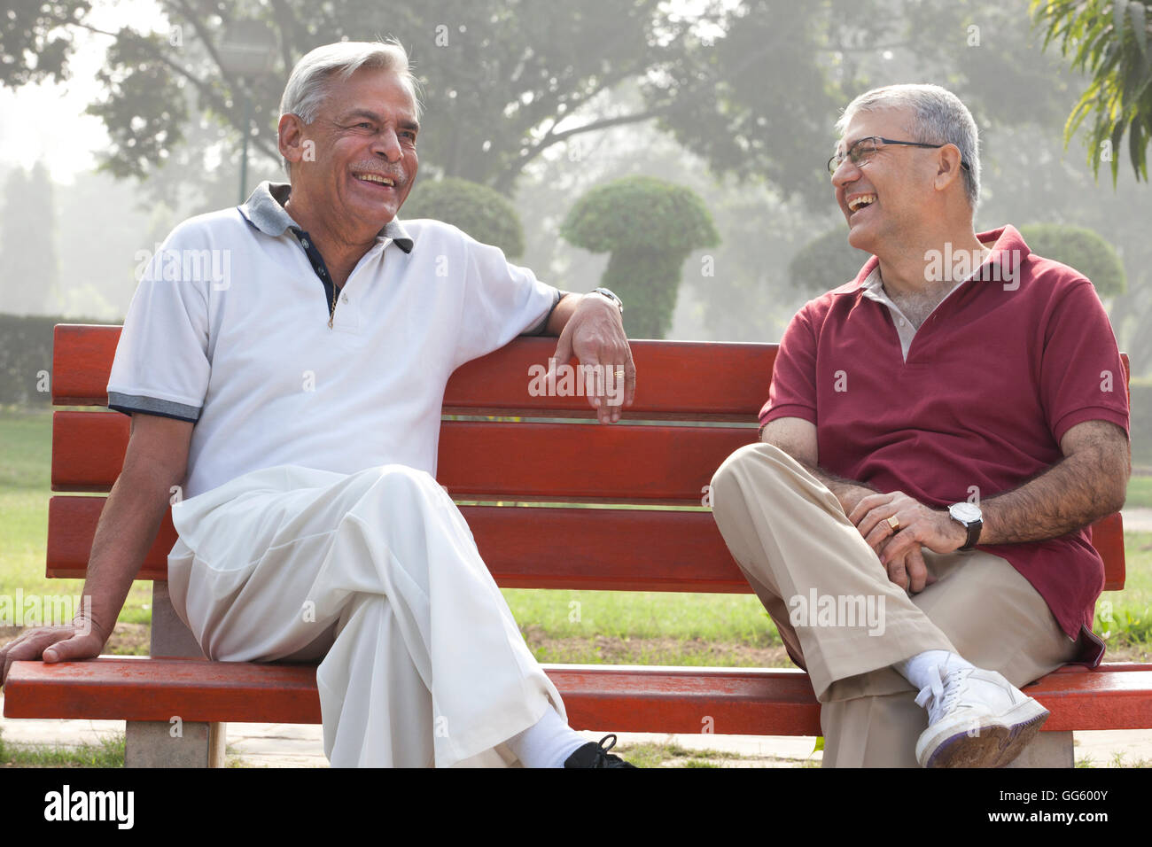 Old men sitting on a bench in a park laughing Stock Photo - Alamy