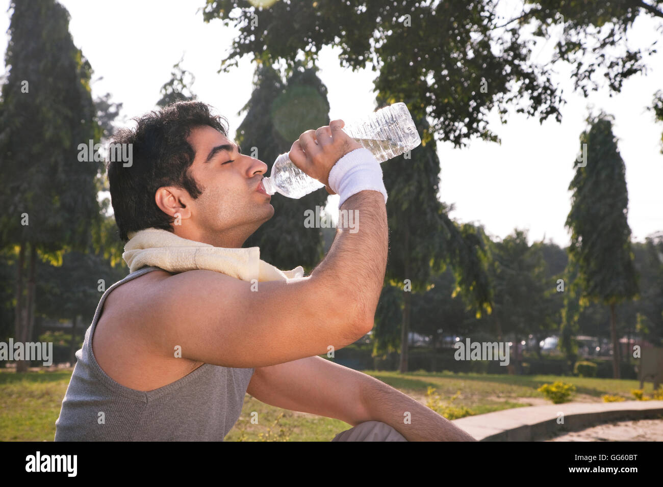 Young man with towel round shoulders drinking water after workout Stock Photo
