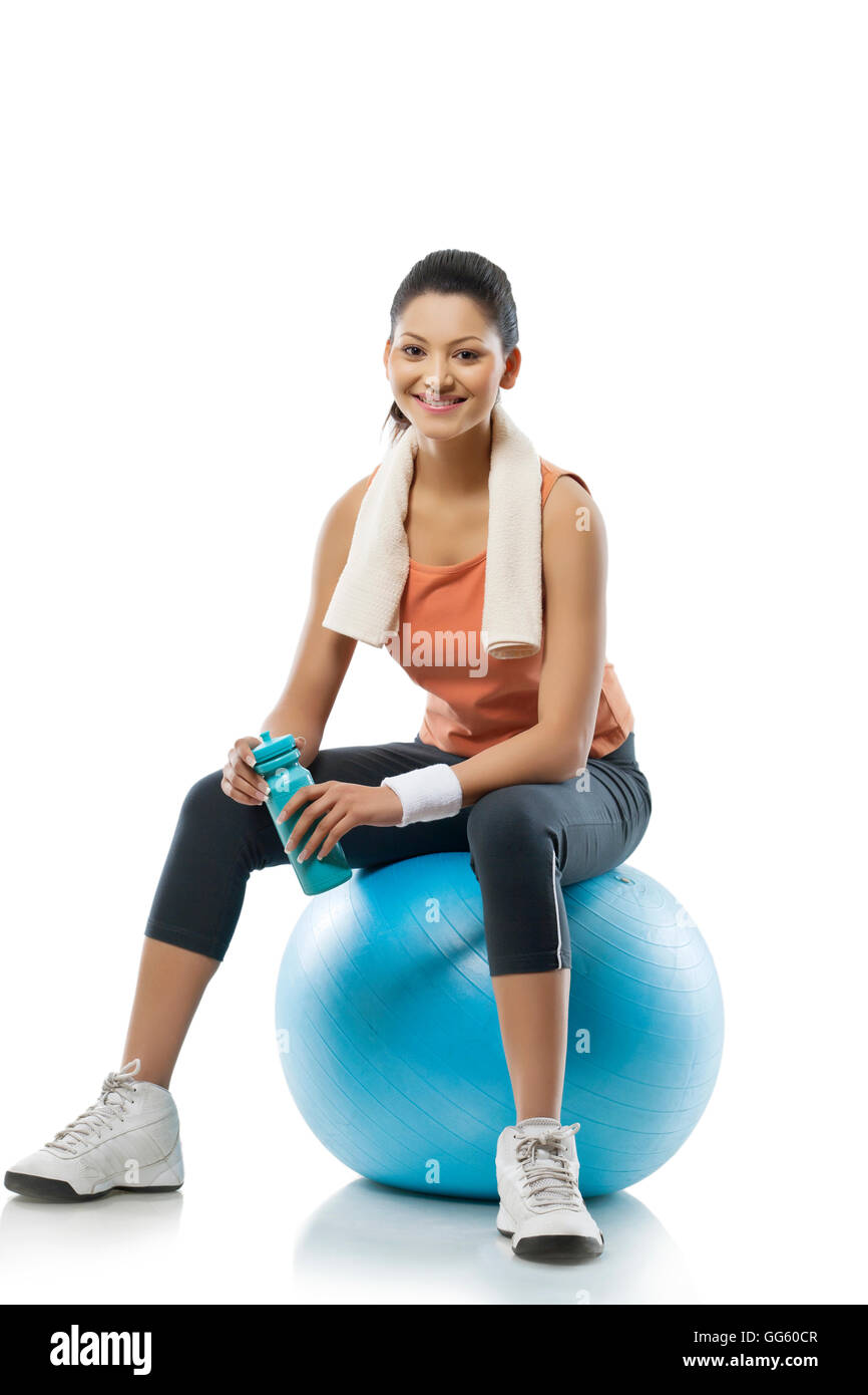Portrait of young woman sitting on a fitness ball after workout over white background Stock Photo