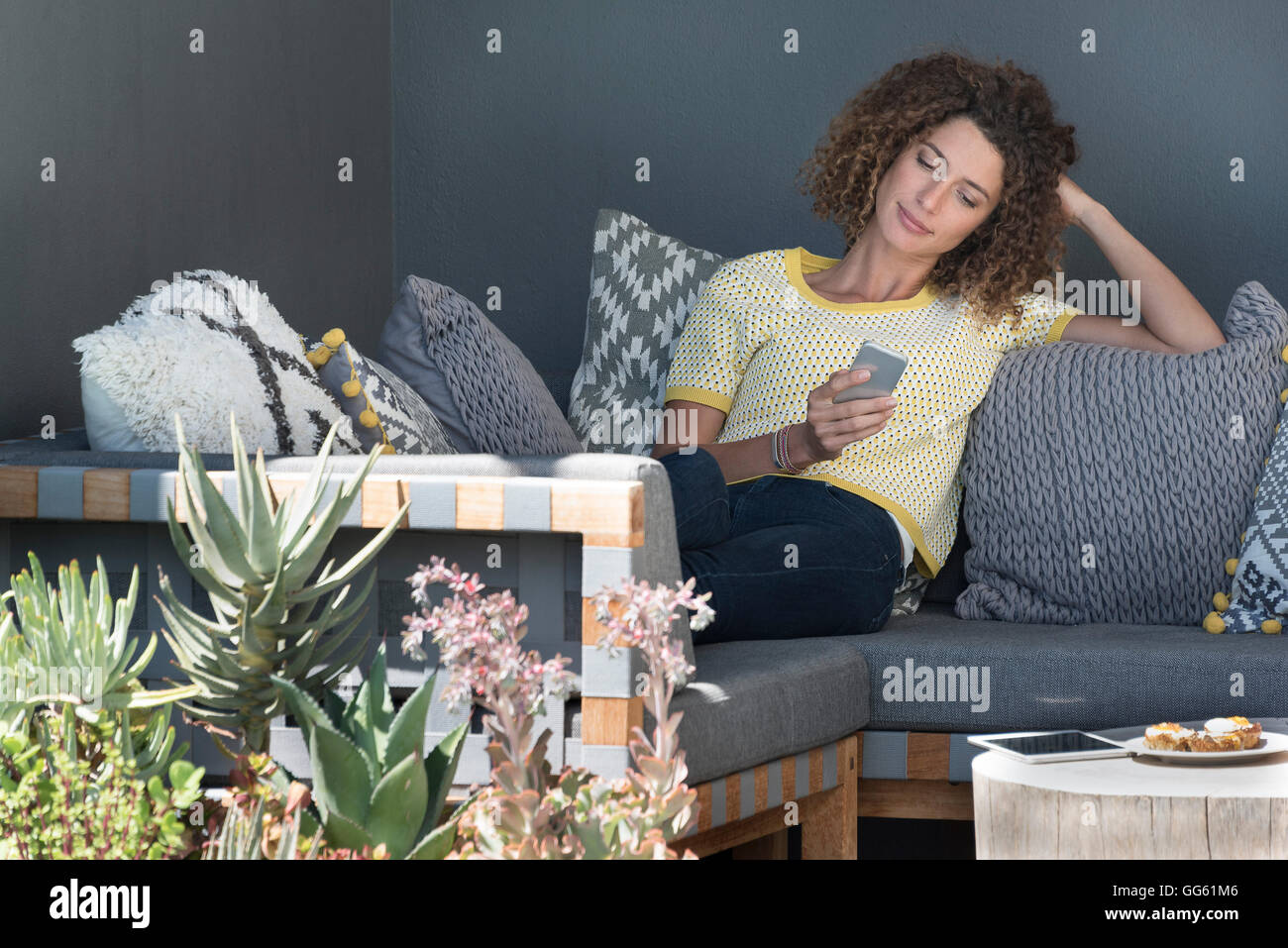 Woman sitting on a couch using a smartphone Stock Photo - Alamy