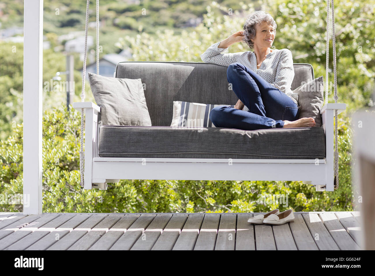 Happy mature woman sitting on a swing in a porch Stock Photo - Alamy