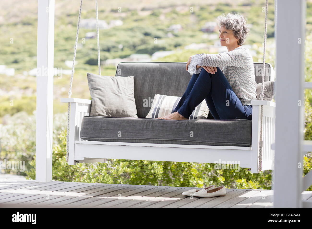 Mature woman sitting on a swing in a porch Stock Photo - Alamy