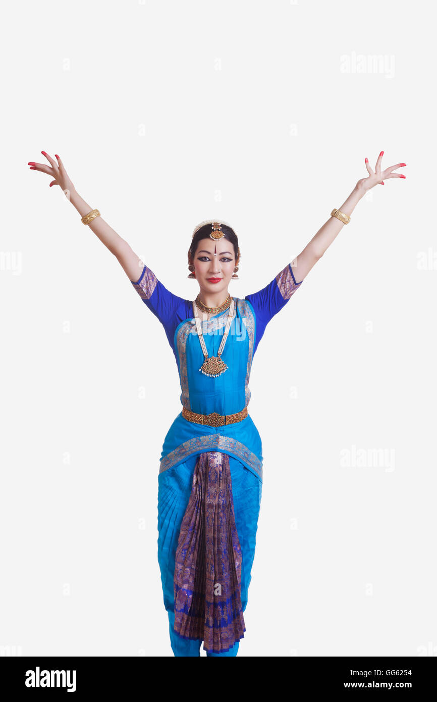 Portrait of dancer with arms raised performing Bharatanatyam against white background Stock Photo