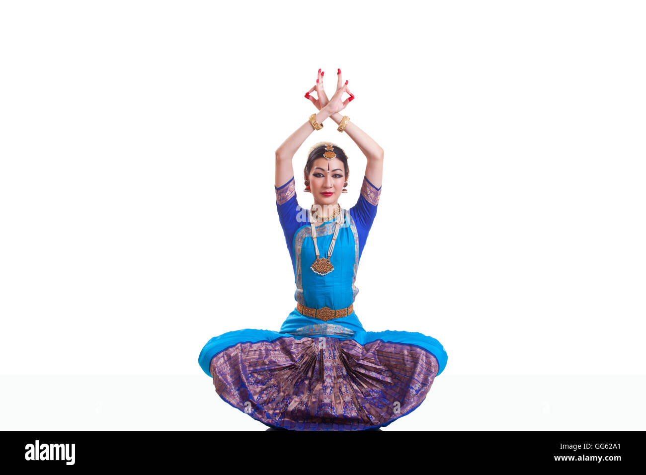 Portrait of dancer with arms raised performing Bharatanatyam isolated over white background Stock Photo