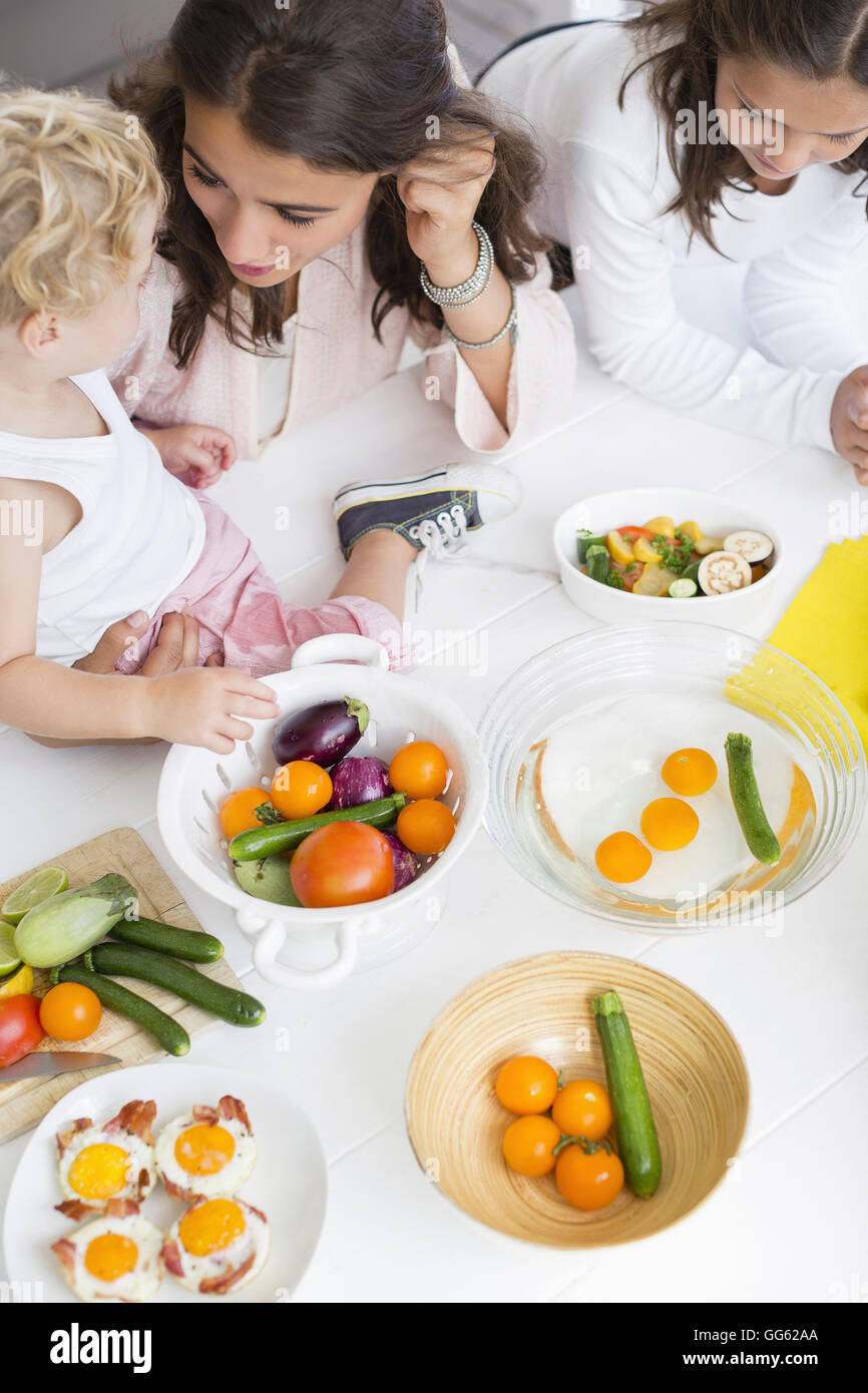 Happy young family preparing vegetables at home Stock Photo