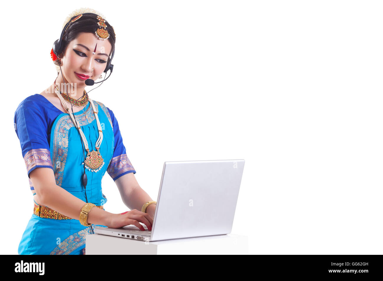 Bharatanatyam dancer wearing headset while using laptop over white background Stock Photo