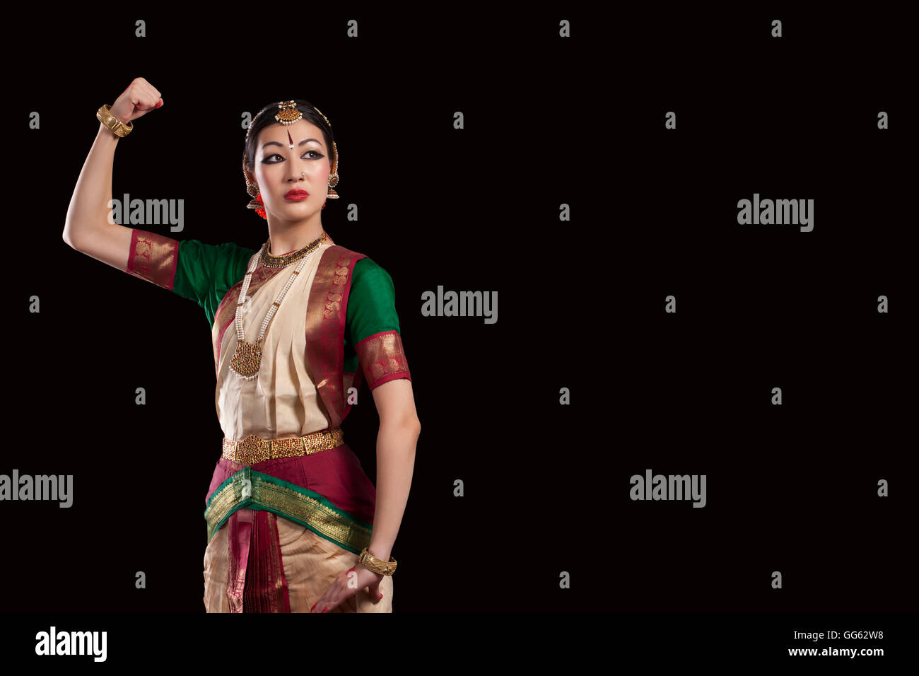 Young Bharatanatyam dancer flexing muscle over black background Stock Photo