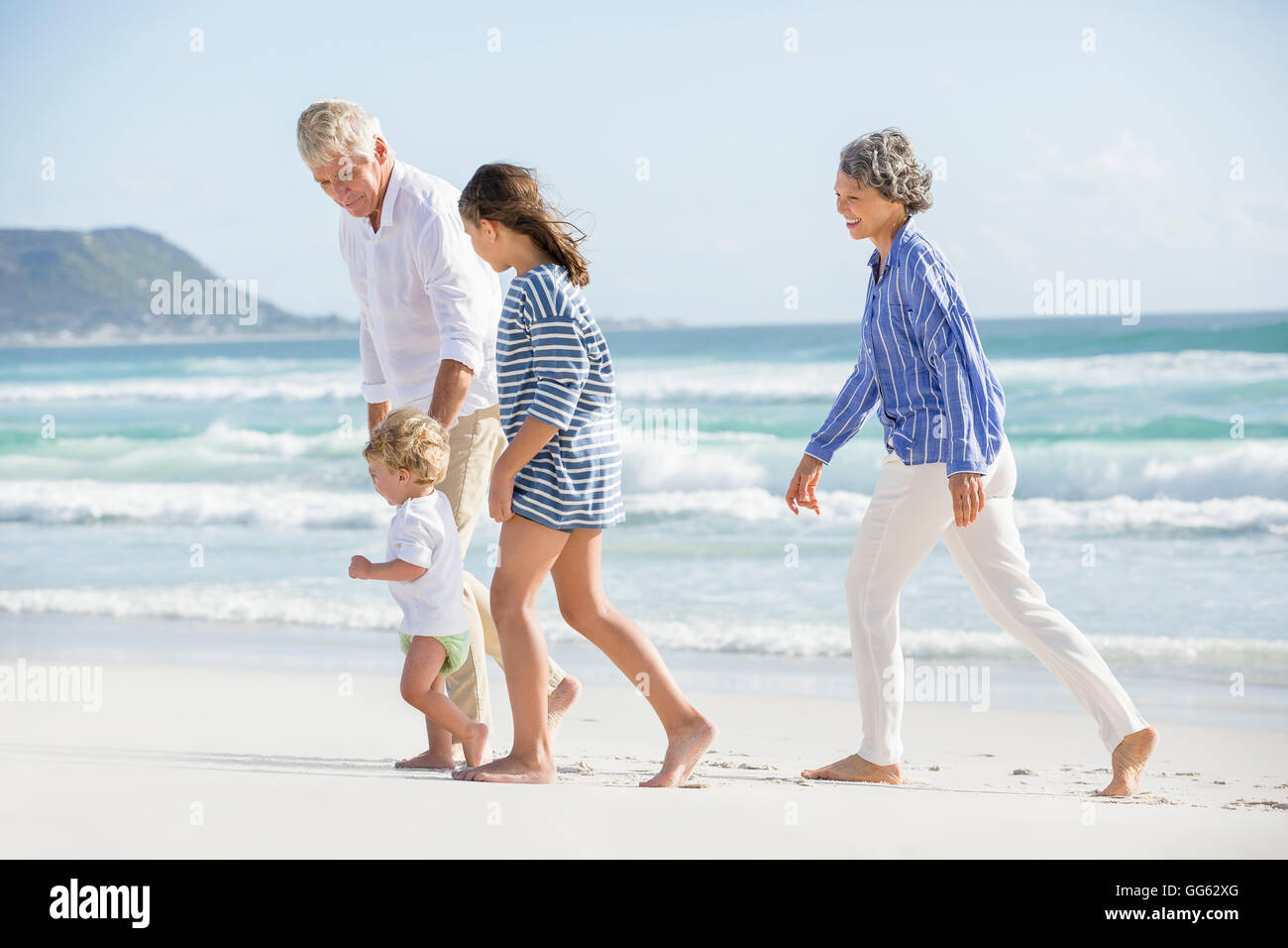 Old couple walking on the beach with their grand children Stock Photo