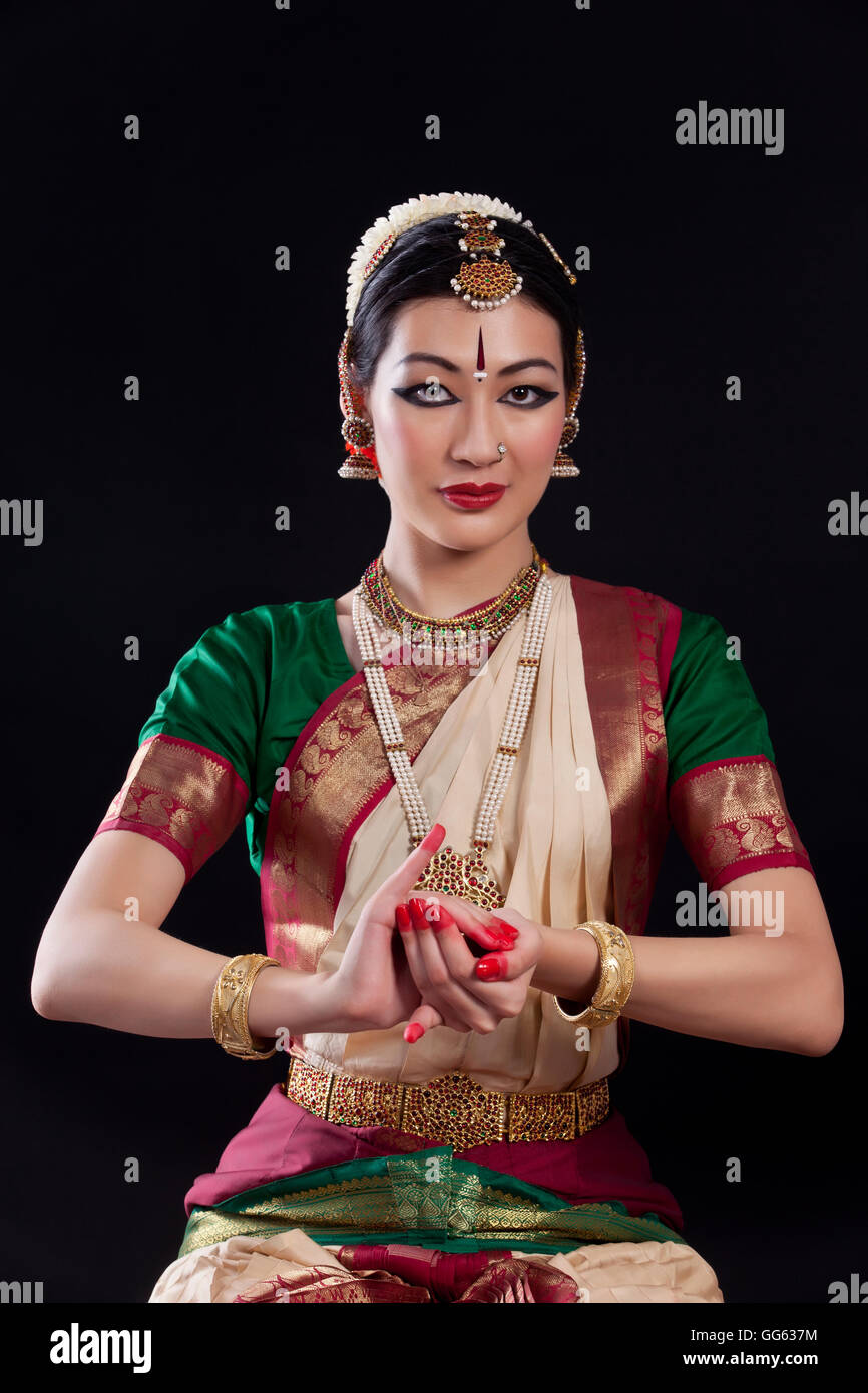 Portrait of young woman making Bharatanatyam gesture called Samputa on black background Stock Photo