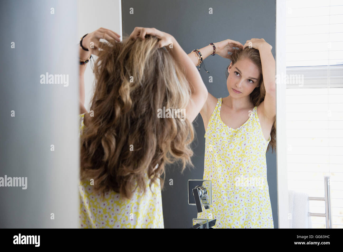 Teenage girl examining her hair in mirror Stock Photo - Alamy