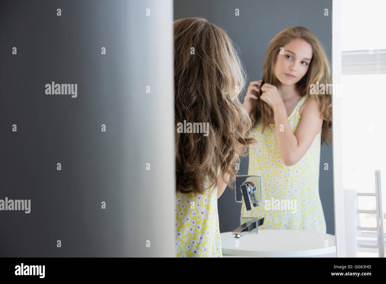 Teenage girl examining her hair in mirror Stock Photo - Alamy