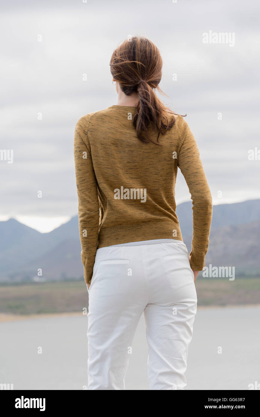 Rear view of a woman standing at lakeshore looking at view Stock Photo ...