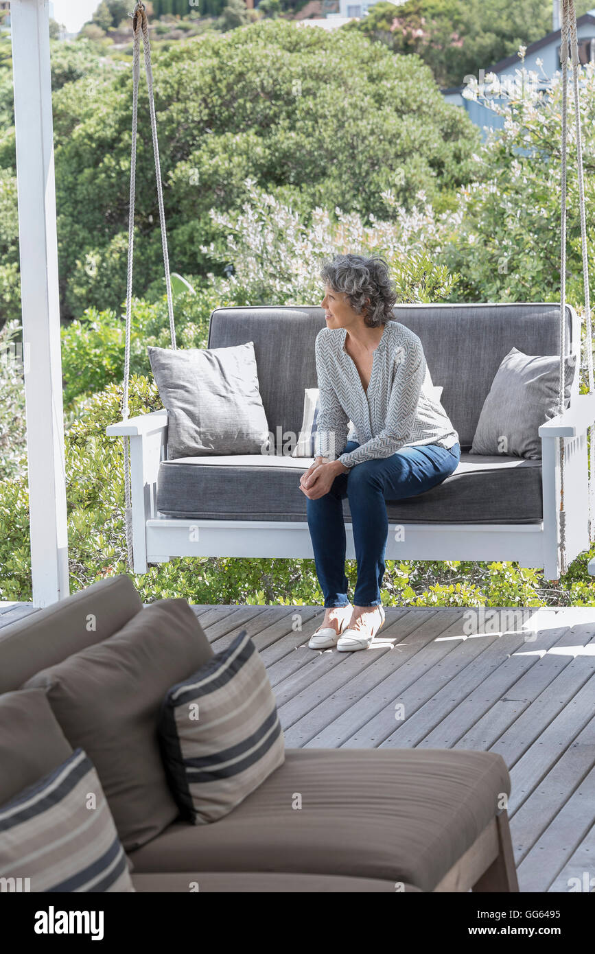Happy woman relaxing on swing chair at porch Stock Photo - Alamy