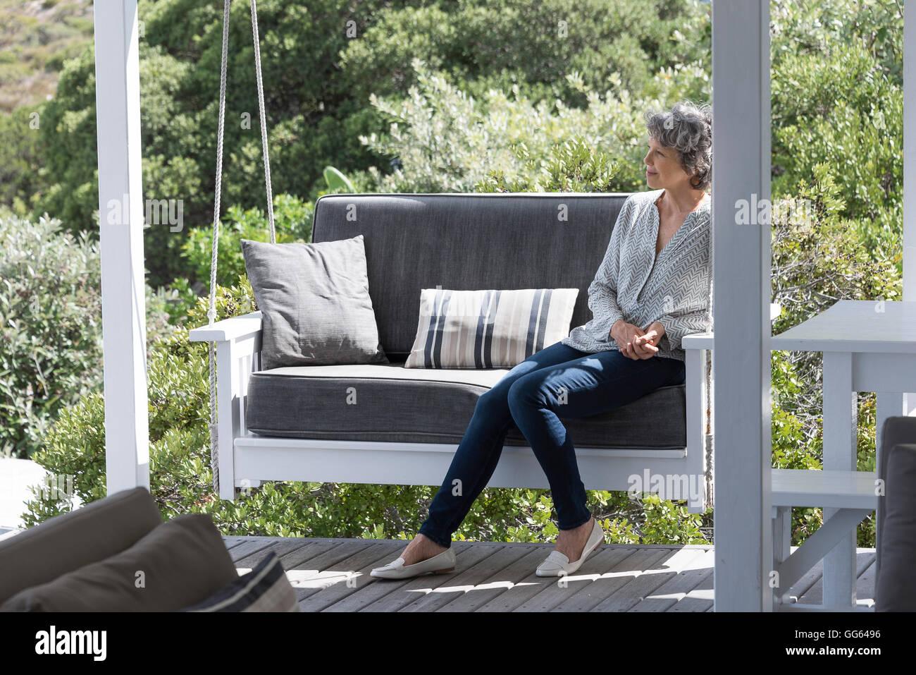 Happy woman relaxing on swing chair at porch Stock Photo - Alamy