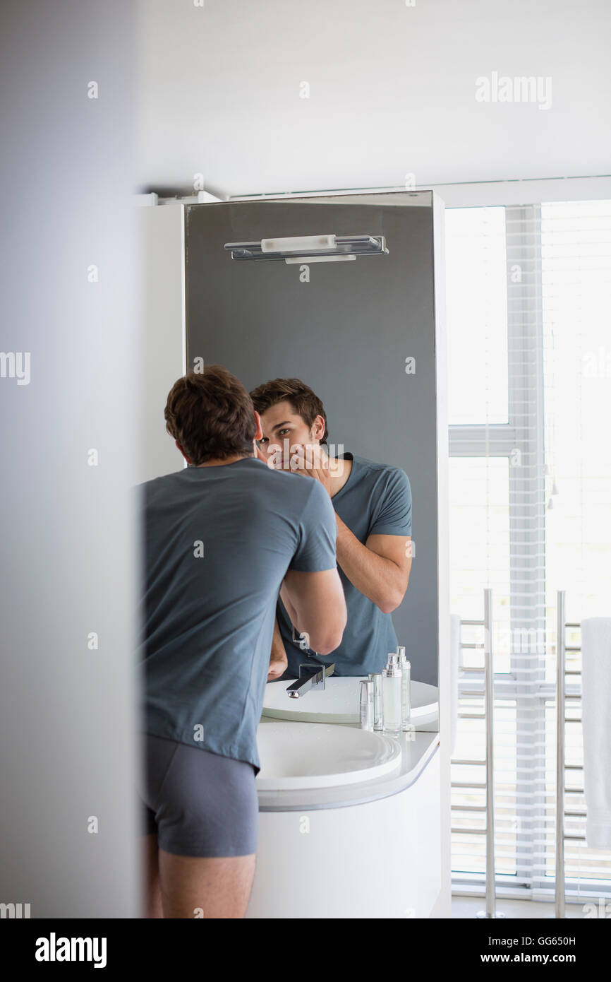 Young checking his face in mirror Stock Photo Alamy