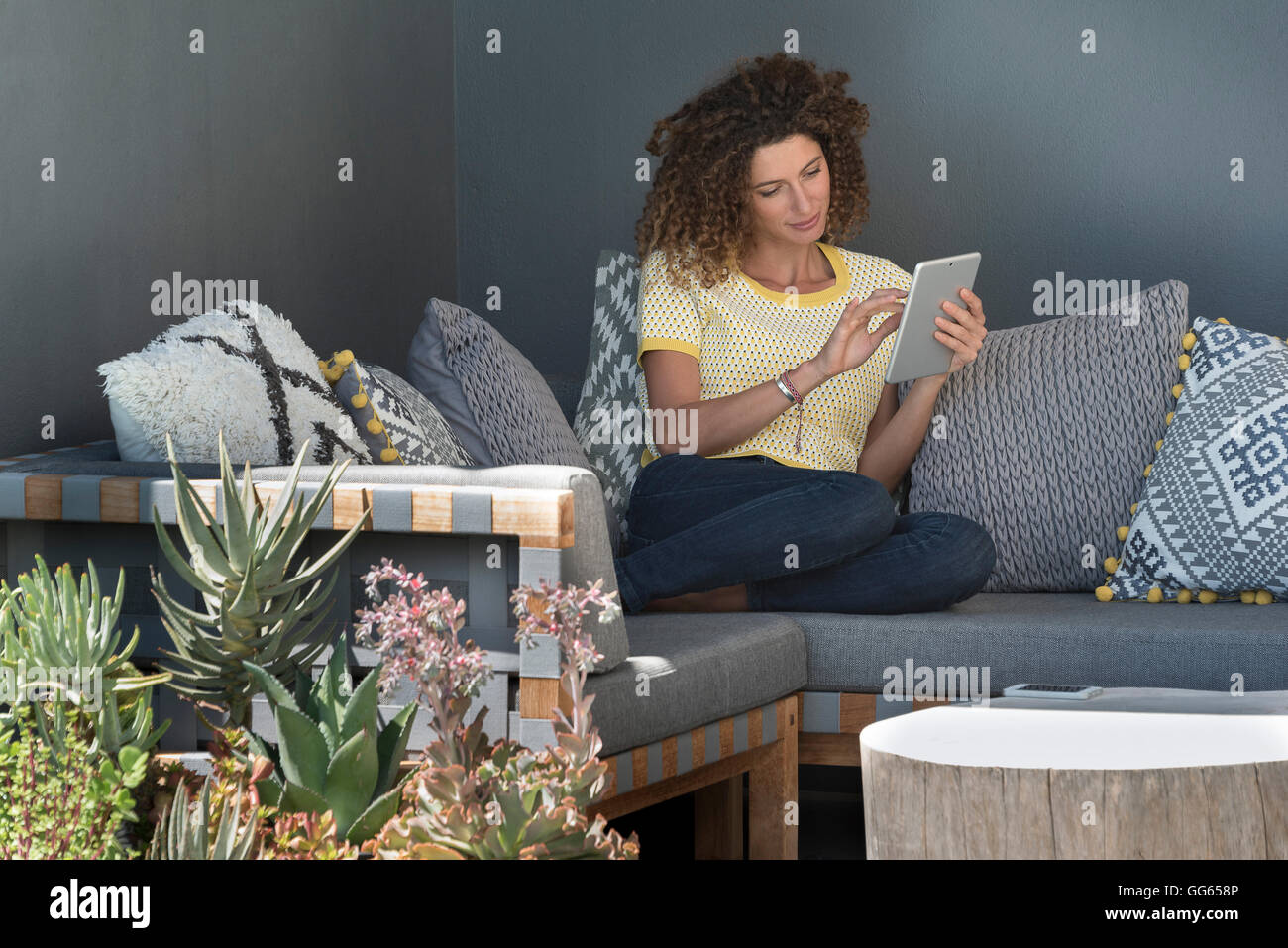 Woman sitting on a couch using a digital tablet Stock Photo - Alamy