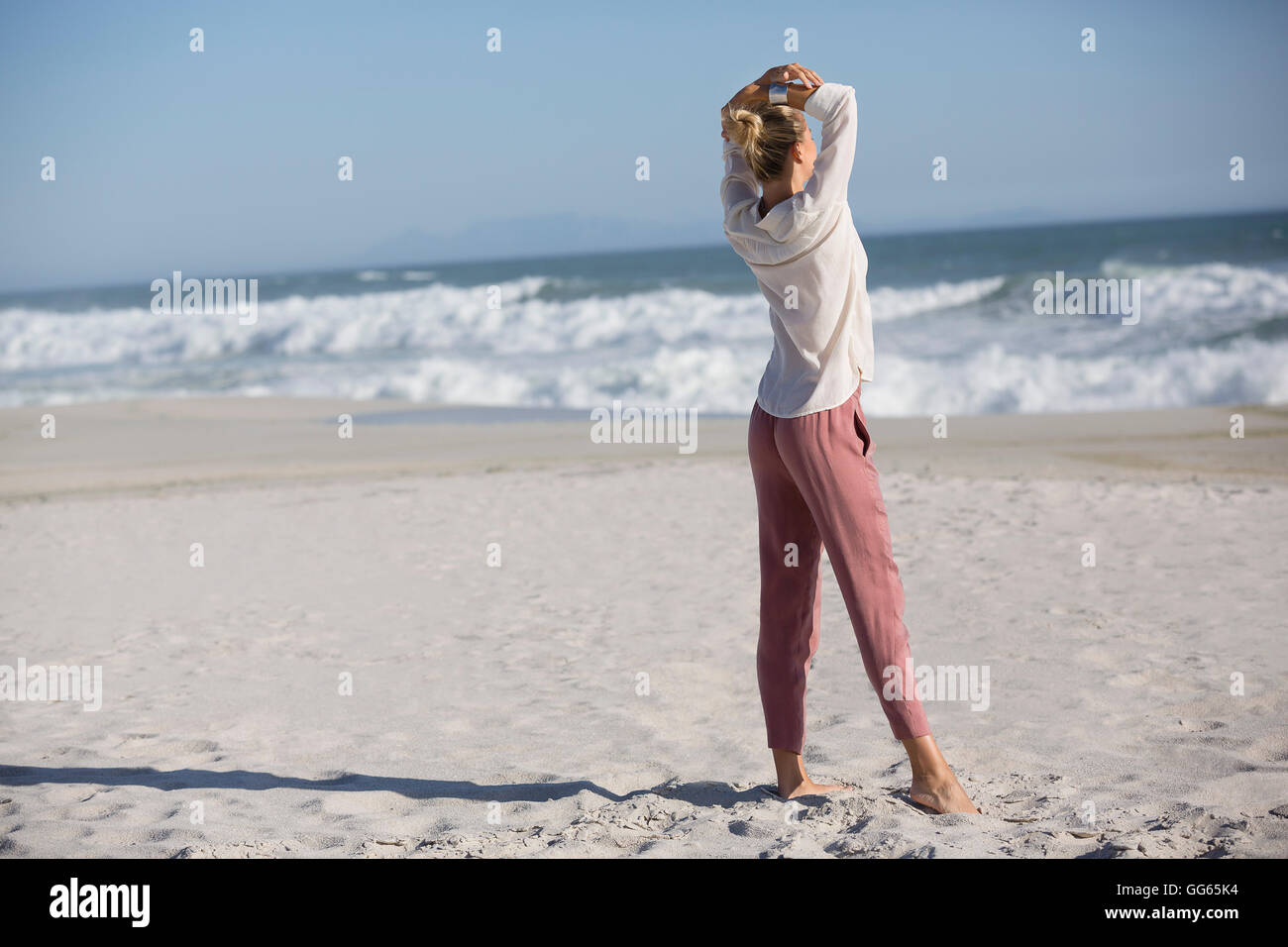 Beautiful young woman standing on sunny beach Stock Photo - Alamy