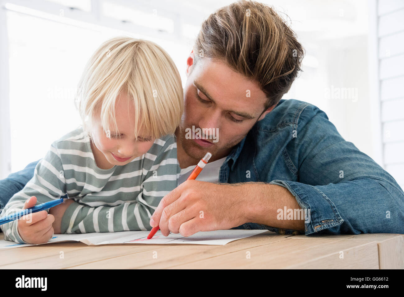 Father and son doing homework on table Stock Photo - Alamy