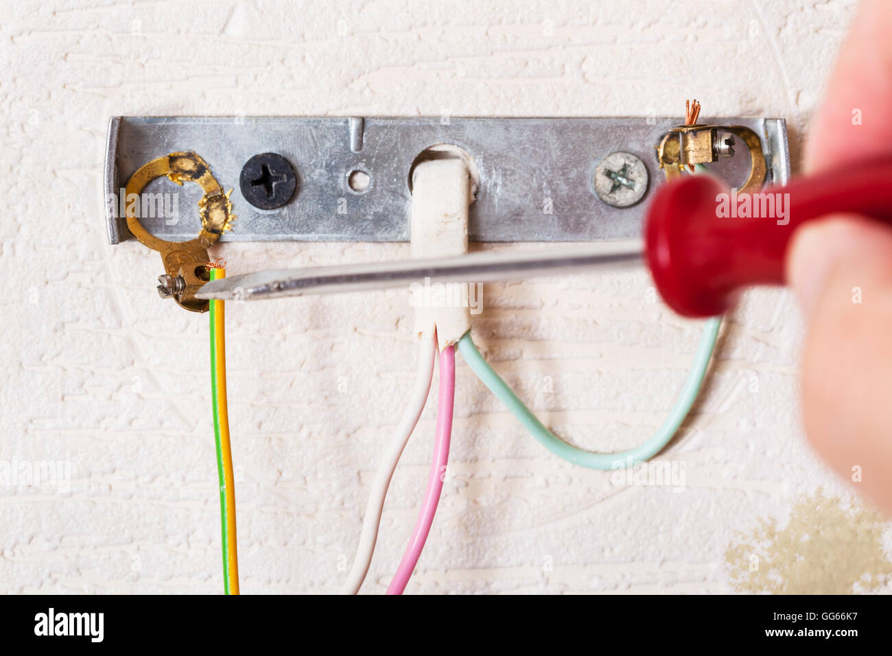 Electrician repairs wiring in wall light close up indoor Stock Photo