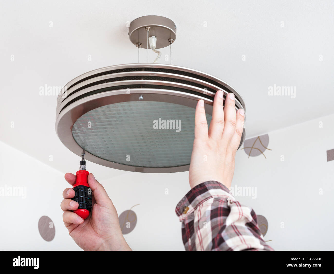Electrician repairs round ceiling light in room Stock Photo - Alamy