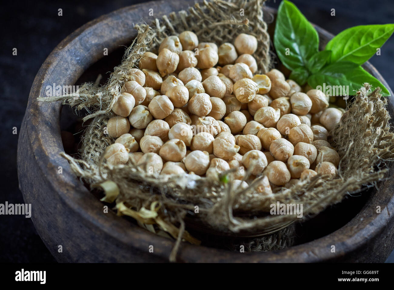Garbanzo beans (chickpeas) with basil in clay bowl on black rustic background Stock Photo
