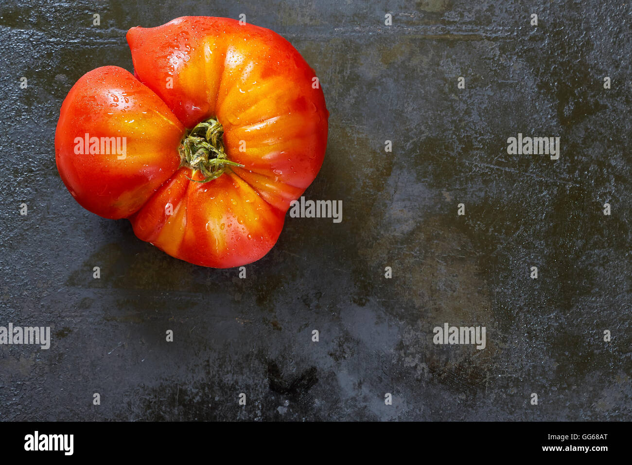 Imperfect organic tomato on black rustic metallic background. Top view with plenty of copy space Stock Photo