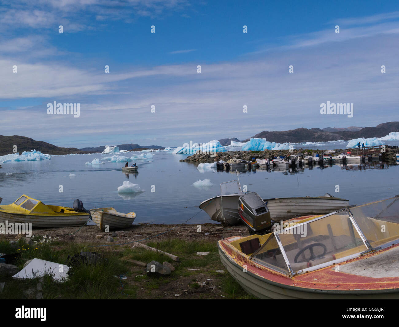 Two fisherman returning to harbour from iceberg covered Tunulliarfik Fjord Narsaq Southern Greenland small fishing community on a lovely calm July day Stock Photo