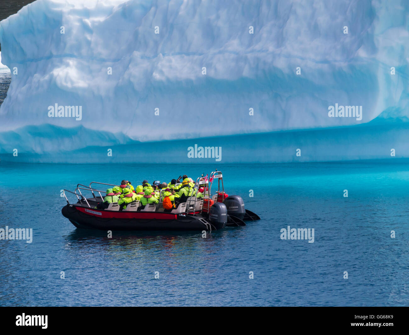 Group of cruise ship tourists close to iceberg on Tunulliarfik fjord on Polarcirkel boat Southern Greenland on a lovely sightseeing day Stock Photo
