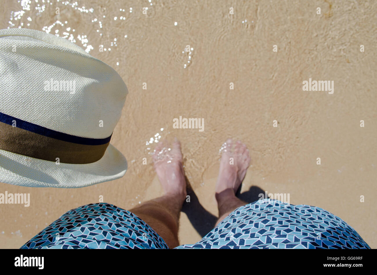 Man walking on the beach with the hat in hand Stock Photo