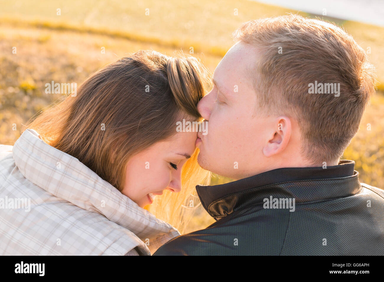 Sweet kiss. Handsome young man kissing his girlfriend on forehead in autumn  park Stock Photo - Alamy