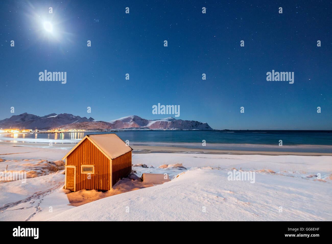 Moonlight on a typical fishermen cabin surrounded by snow, Ramberg, Flakstad, Nordland County, Lofoten Islands, Arctic, Norway Stock Photo