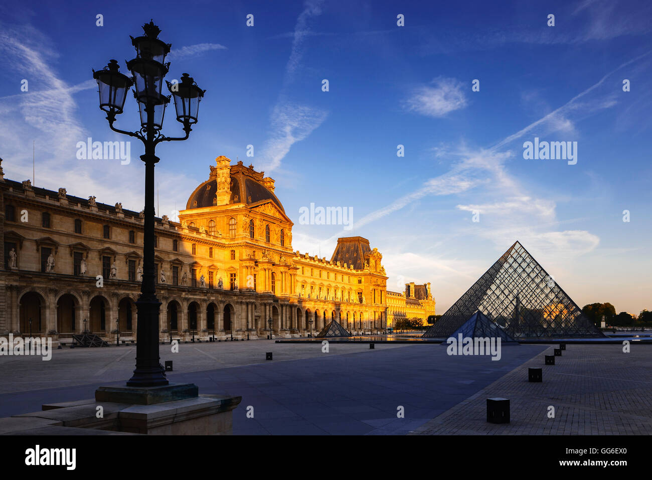 Dawn light illuminates the Louvre Palace bordering the Napoleon Courtyard and Louvre Pyramid, Paris, France, Europe Stock Photo