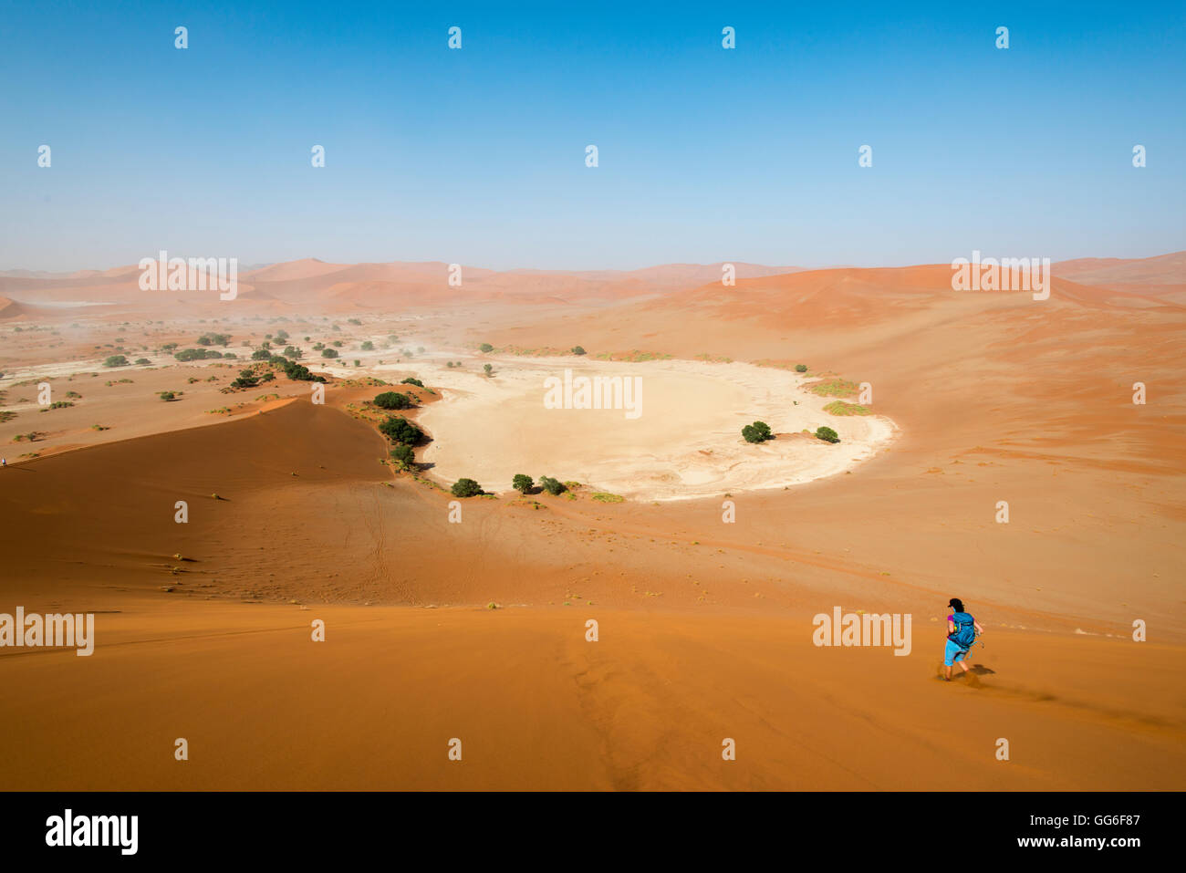 A woman runs down from the summit of Sossusvlei sand dune, Namibia, Africa Stock Photo