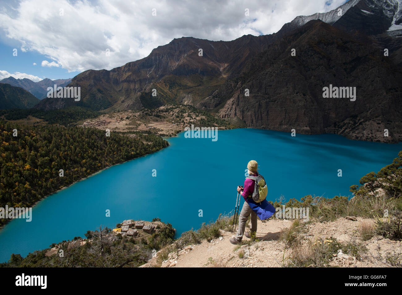 A trekker stands above the turquoise blue Phoksundo Lake in the Dolpa region, Himalayas, Nepal, Asia Stock Photo