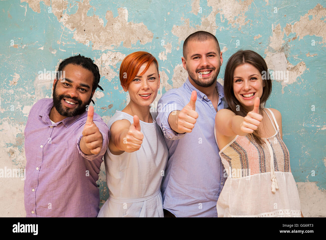 Young multiethnic people posing in front of a grunge wall with a thumbs up Stock Photo