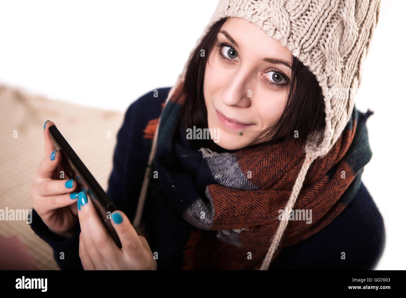 Girl holding smartphone with a empty blank screen monitor and a cup of coffee or tea on the background in a home atmosphere, hipster using in hands a smart phone with space for information, blur Stock Photo