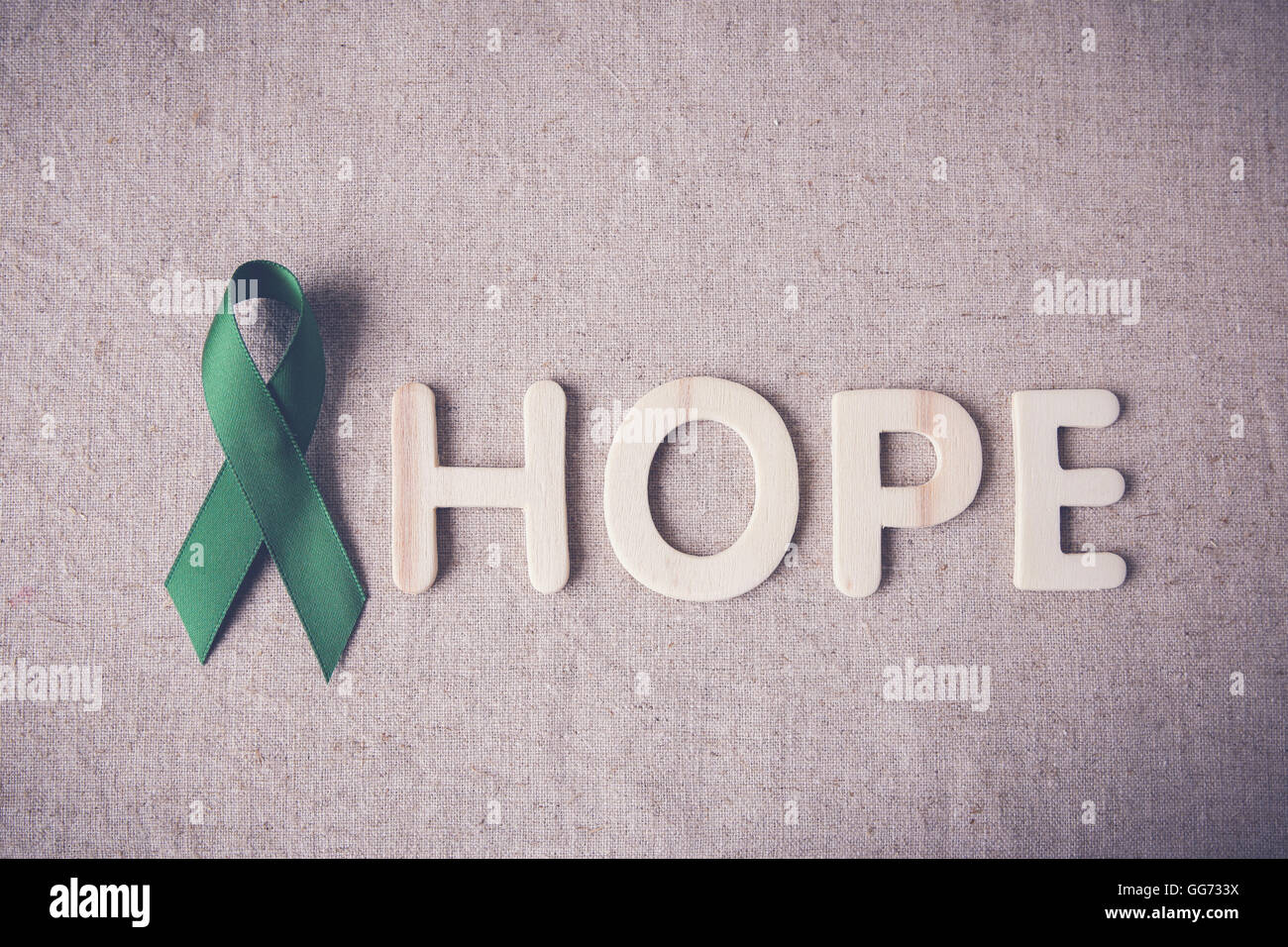 Green Ribbon with HOPE wooden word, cancer awareness, Liver, kidney cancer awareness Stock Photo