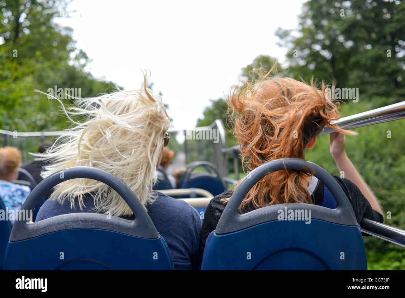 It's windy on the top deck of an open top bus when it's moving as these two women passengers are finding out. Stock Photo