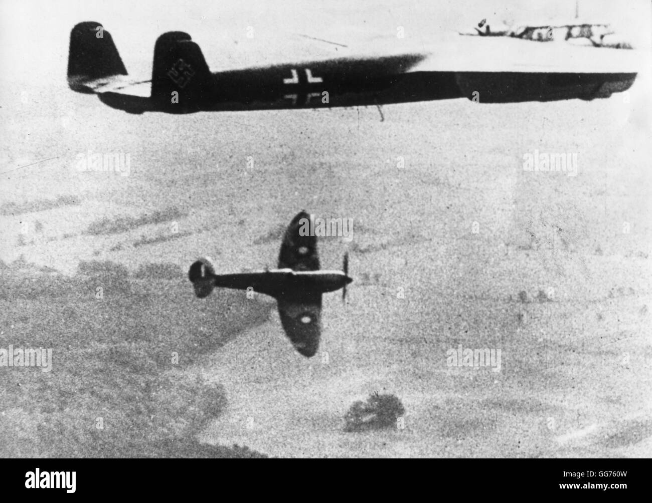 A German airplane, Dornier 'Do-17' type, flies on, while the British Spitfire is forced down after an unsuccessful attack. Stock Photo