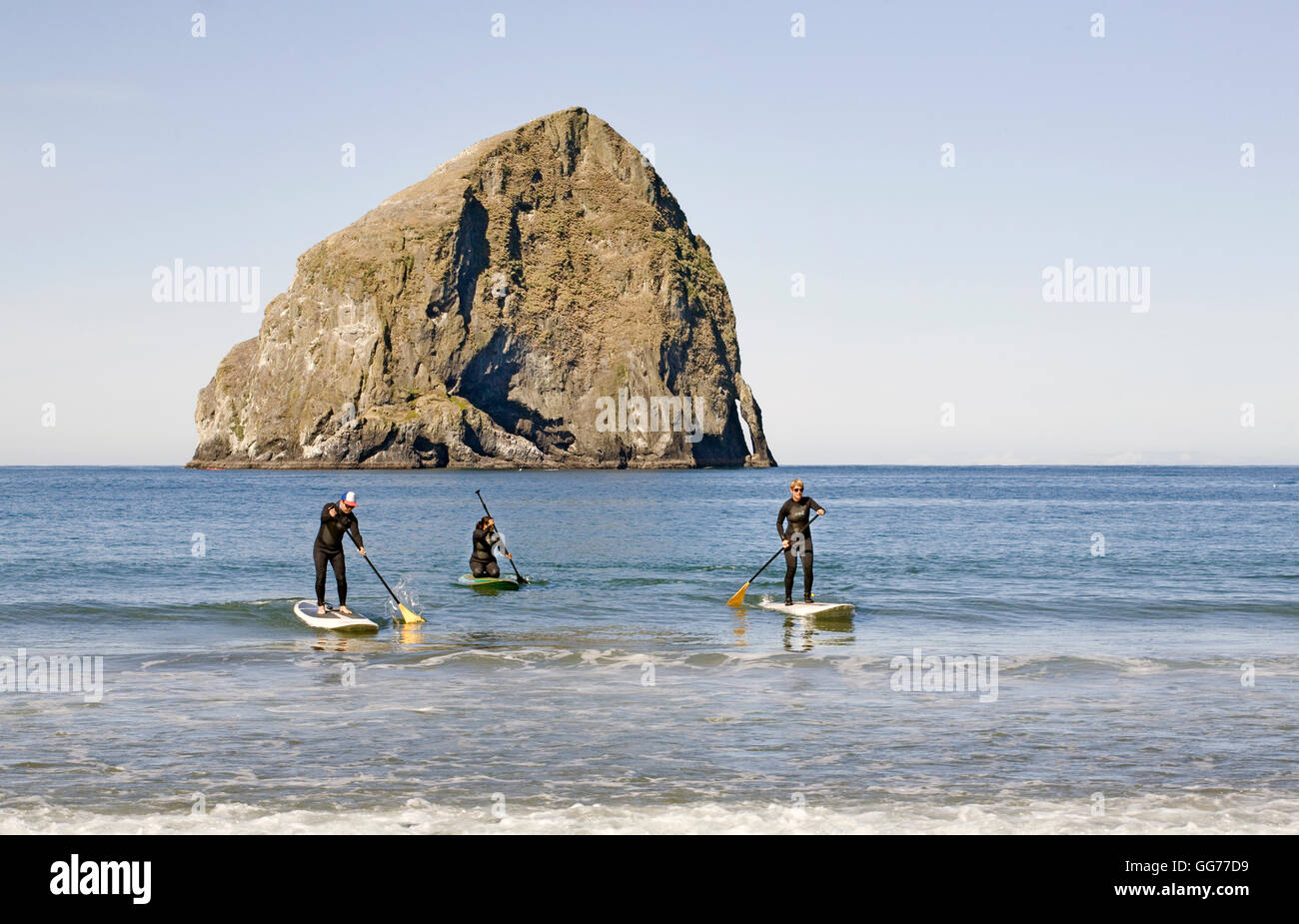 Stand-up paddleboarders near Haystack Rock in Pacific City, Oregon Stock Photo