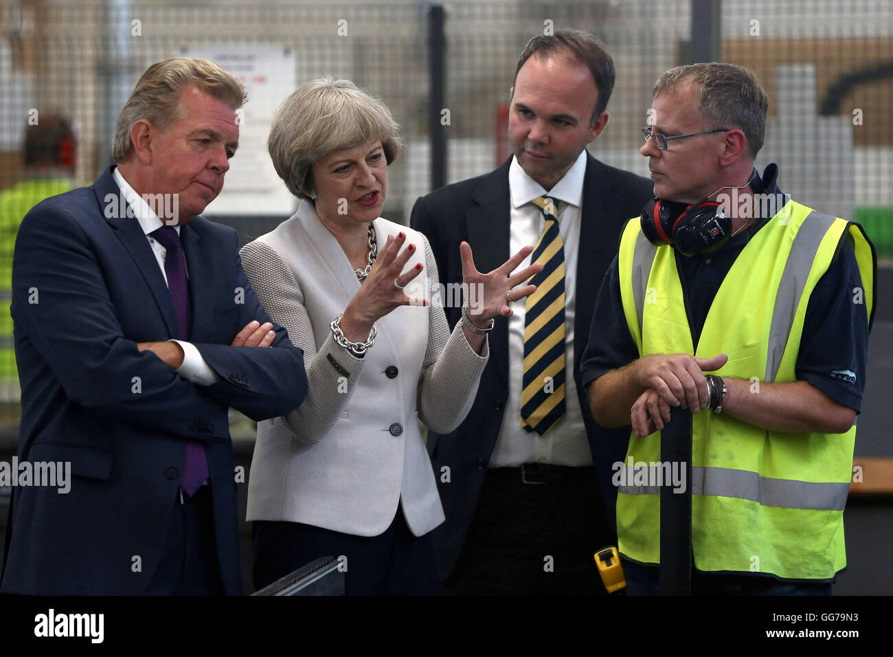Prime Minister Theresa May with Martek Managing Director Derek Galloway (left) and Croydon Central MP Gavin Barwell (2nd right) talk to a worker during her visit to Martek joinery manufacturers in New Addington, Surrey. Stock Photo
