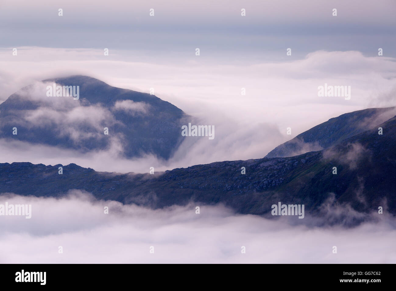 An inversion rolling over a saddle in between two hills at dawn, Loch Quoich, seen from the summit of Sgurr na Ciche, Glen Dessary Stock Photo