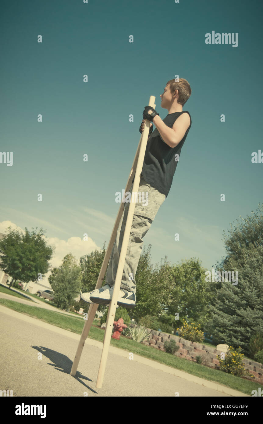 Teenage boy learning to walk on stilts he just finished making. Retro instagram look. Stock Photo